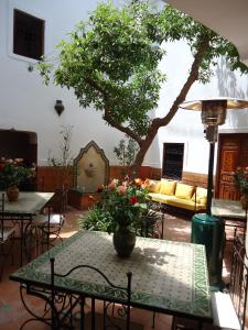 un patio con mesas, sillas y un árbol en Riad Aldiana en Marrakech