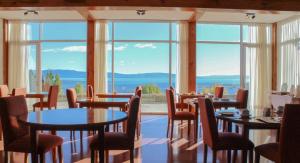 un restaurante con mesas, sillas y ventanas grandes en Terrazas Del Calafate en El Calafate