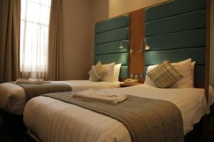 a hotel room with two beds and two lamps at Astors Belgravia in London