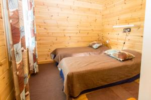 two beds in a room with wooden walls at Resort Naaranlahti Cottages in Naaranlahti