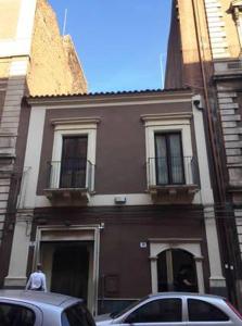 un edificio con coches estacionados frente a él en Ottomood House Catania, en Catania