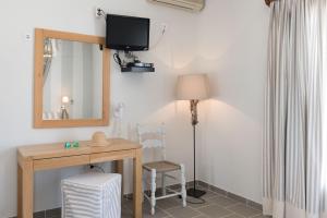 Habitación con escritorio, espejo y lámpara. en Aeolos Apartments, en Kamarai