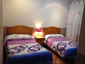 a bedroom with two beds and a table with a lamp at Pensión Flipper in Bullas