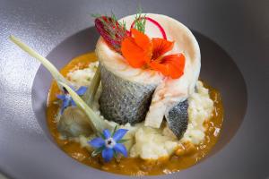 un plato de comida con un plato de pescado con flores. en Le Relais de Farrou, en Villefranche-de-Rouergue