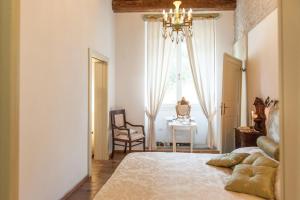 a bedroom with a bed with a chandelier and a chair at Borgo dei Salinari Apartments in Cervia