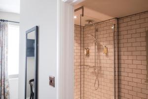 a bathroom with a shower with white tile at Hinds Head in Aldermaston