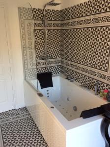 e bagno con vasca e parete piastrellata. di Manoir de kermilven a Trémeven
