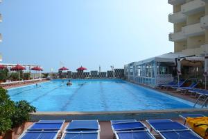 una grande piscina con sedie blu e ombrelloni di Perticari a Pesaro