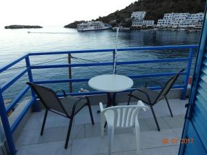 
a dining room table with chairs and a blue umbrella at Scirocco Rooms in Loutro
