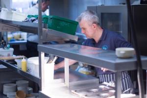 un homme debout dans une cuisine préparant la nourriture dans l'établissement Yorkshire Bridge Inn, à Bamford