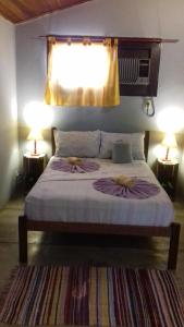 um quarto com uma cama com 2 candeeiros e uma janela em Maracujá Hostel em Paraty