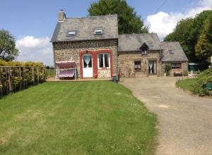 an old stone house with a grass yard at La Perruche Holiday Gite in Heussé