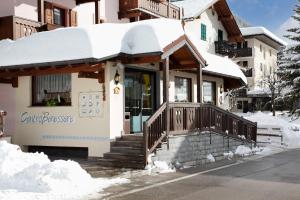 dom pokryty śniegiem z werandą w obiekcie Hotel Villa Emma w Madonna di Campiglio