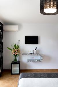 Habitación con cama y TV en la pared. en Hostal Alhambra - Adults Only, en Nerja
