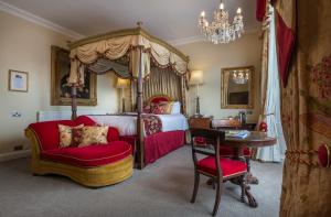 a bedroom with a canopy bed and a table and chair at The Golden Fleece Hotel, Thirsk, North Yorkshire - The Coaching Inn Group in Thirsk