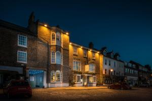 een groot bakstenen gebouw met 's nachts verlichting bij The Golden Fleece Hotel, Thirsk, North Yorkshire in Thirsk