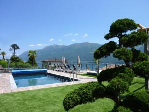 a swimming pool with chairs and a view of the mountains at Apartments Casa Ghiggi in Brissago