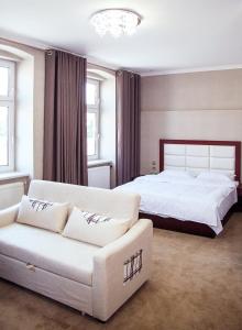 a bedroom with a white bed and a white couch at Hotel MUSE in Sankt Pölten