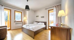 una camera con letto, scrivania e finestre di Apartament Madera Polna a Zakopane