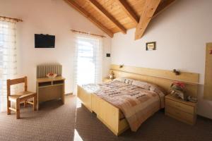 ein Schlafzimmer mit einem Bett und einem Stuhl in einem Zimmer in der Unterkunft Hotel Vallechiara in Moena