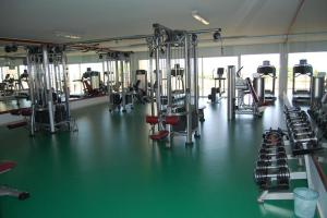 een fitnessruimte met een groene vloer en rijen machines bij Asilah Marina Golf Appart in Asilah