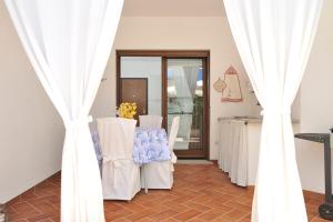 een kamer met witte gordijnen en een tafel met stoelen bij La casa di Leo in Santa Maria Navarrese
