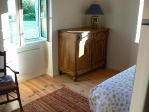 1 dormitorio con armario de madera y ventana en La petite maison de Clotilde, en Creysse