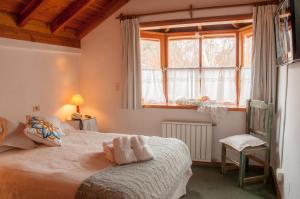 1 dormitorio con cama, ventana y silla en Hostería El Arbol Duende en San Martín de los Andes