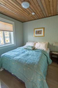 un letto in una camera da letto con soffitto in legno di Olstind in Sakrisøy a Reine