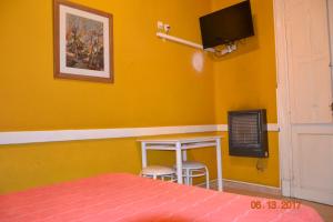 a bedroom with a yellow wall with a bed and a tv at Hotel Victoria in Bahía Blanca