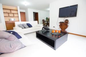 een woonkamer met een witte bank en een tv bij San Fernando Suite 201 - Livin Colombia in Cali