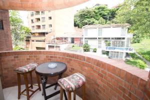 un balcón con 2 taburetes y una mesa en una pared de ladrillo en San Fernando Suite 201 - Livin Colombia, en Cali