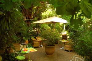 a patio with chairs and tables and an umbrella at Le Windsor, Jungle Art Hotel in Nice