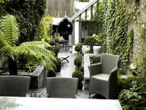 einen Garten mit Stühlen und Pflanzen und ein Haus in der Unterkunft Au Grey d'Honfleur in Honfleur