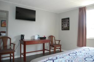 a hotel room with a desk and a bed and chairs at Edge of the Avalon Inn in Trepassey