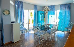 フエンヒロラにあるÁtico con gran terrazaのダイニングルーム(青いカーテン、ガラスのテーブルと椅子付)