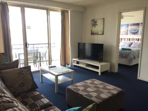 a living room with a couch and a television at Mermaid Beach Apartment in Gold Coast