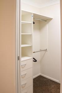 a walk in closet with white shelves at Brand New Executive Living 36 in Bundamba