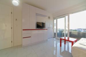 ein weißes Wohnzimmer mit einem TV und einem roten Tisch in der Unterkunft Villa JASMINA in Novalja