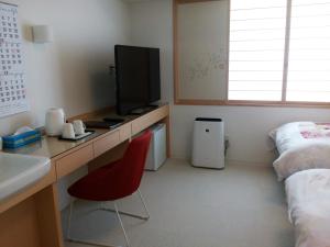 Zimmer mit einem Schreibtisch, einem TV und einem Bett in der Unterkunft Hotel Nishimura in Fuji