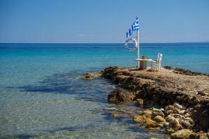 a sign on a rocky island in the ocean at Fiore Beach Studios in Vasilikos