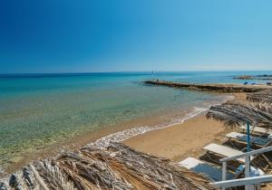 a beach with some chairs and the ocean at Fiore Beach Studios in Vasilikos