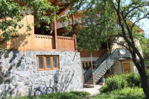 a house with a stone wall and a staircase at Irina's Guesthouse in Mestia