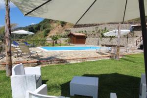 a pool with white chairs and an umbrella at Profetina Village in Motta Camastra