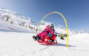 dos niños montados en un trineo en la nieve en Panorama, en Blatten bei Naters