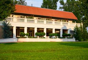 ein weißes Gebäude mit einem orangenen Dach und einem Hof in der Unterkunft Arcanum Hotel in Békéscsaba
