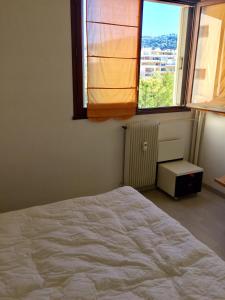 1 dormitorio con cama blanca y ventana en AGENCIA appartement 2 chambres LE CORFOU, en Cannes