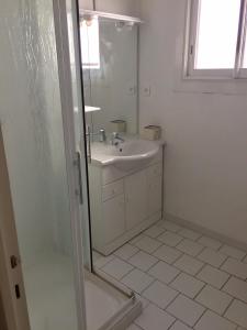 y baño blanco con lavabo y ducha. en AGENCIA appartement 2 chambres LE CORFOU, en Cannes