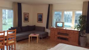 uma sala de estar com um sofá e uma televisão em Hotel Landhaus Leuchtfeuer Nordseeinsel Pellworm em Pellworm