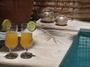 two glasses of orange juice and a lime slice on a table at Riad Safina in Marrakesh